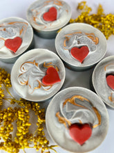 Load image into Gallery viewer, Six frosted grey soaps with red hearts and gold mica  are surrounded by chamomile flowers 